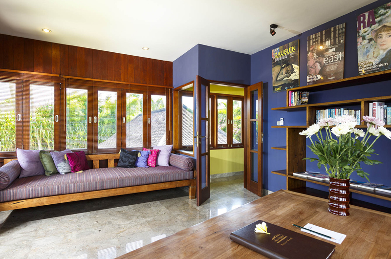 Sitting room at Villa Pushpapuri with a long cushioned daybed, bookshelves and a garden view