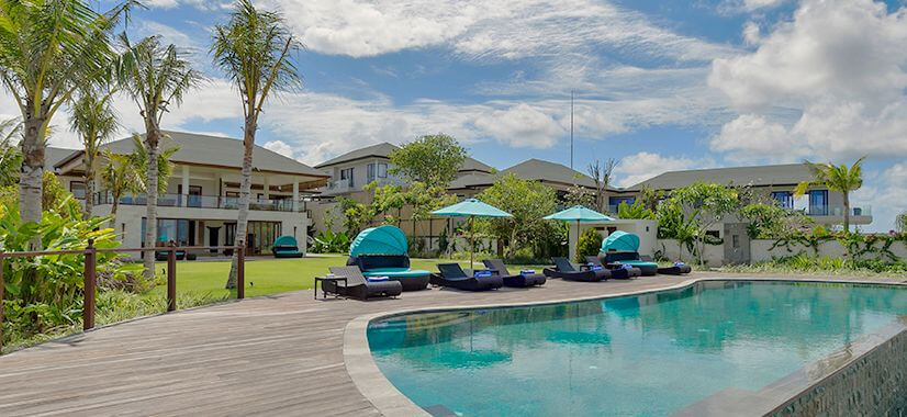 Villa Rose's curved pool deck and garden lawn framed by palm trees