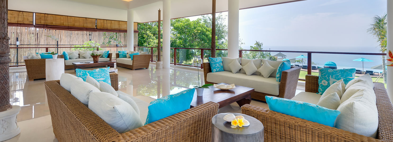 Open-air living pavilion at Villa Rose with rattan sofas facing the ocean view