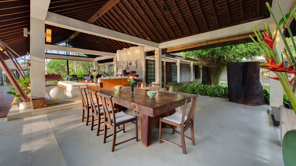The open-air dining pavilion at Villa Samadhana, with a high vaulted timber ceiling and a long solid-wood table