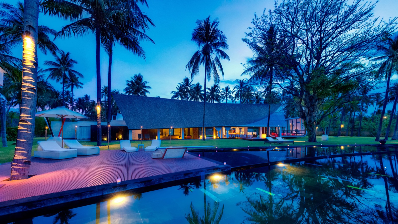 Pool deck, daybeds and the main pavilion lit at dusk at Villa Sapi, Sira Beach, Lombok