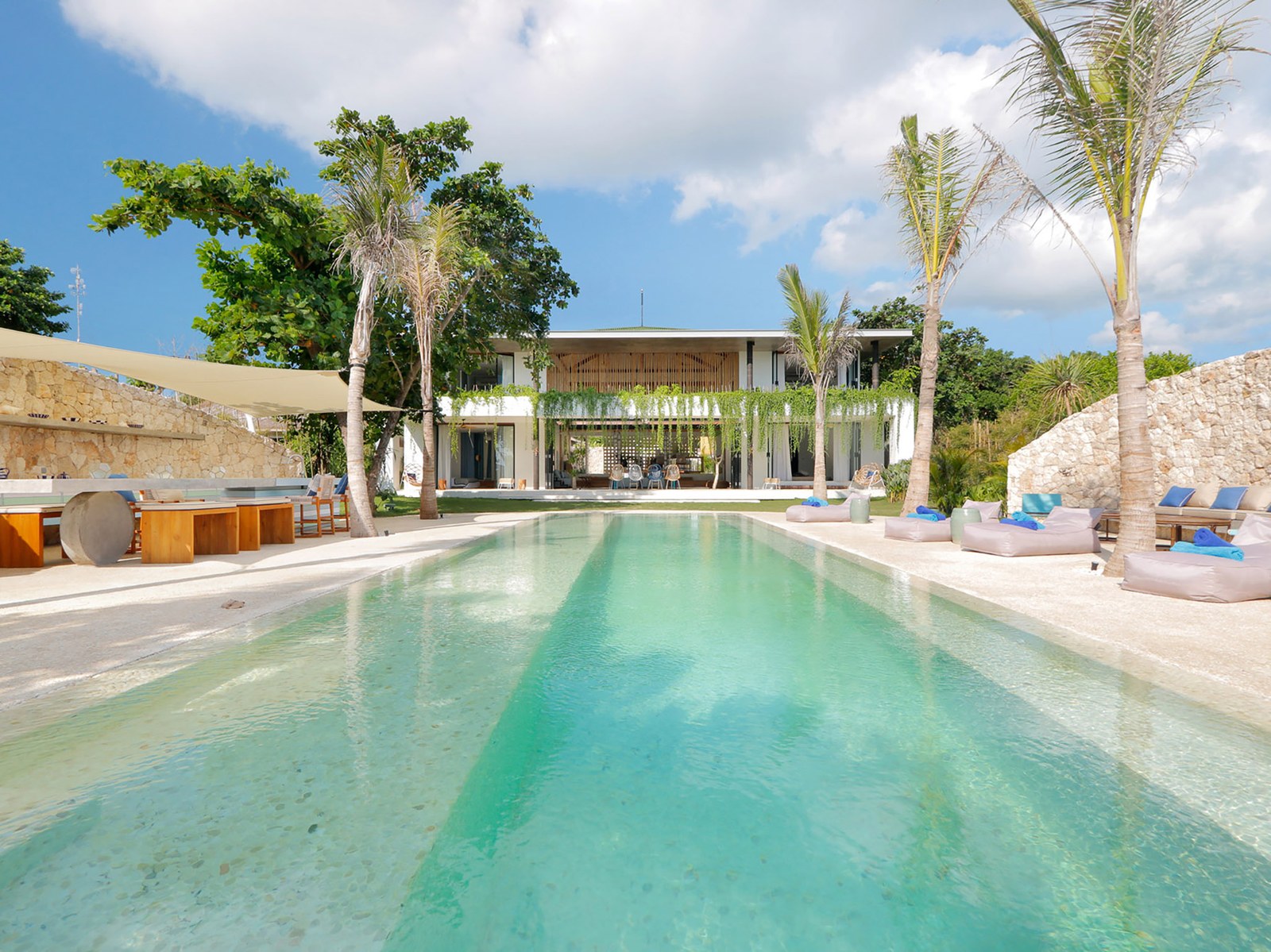 The 15-metre pool running towards the villa pavilion through palms at Villa Seascape, Nusa Lembongan, Bali