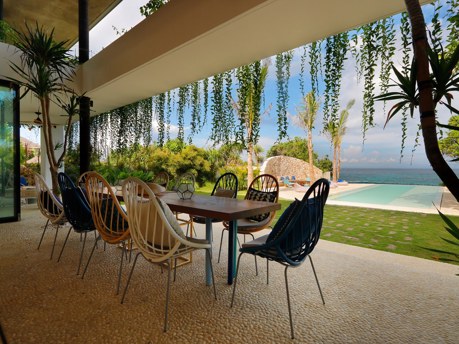 Outdoor dining table under the roofline with the pool and ocean beyond at Villa Seascape, Nusa Lembongan, Bali