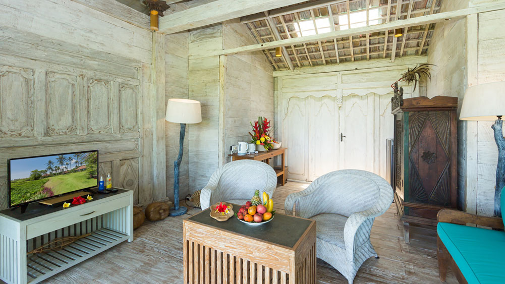 Whitewashed timber joglo living space at Villa Sungai Tinggi, with wicker chairs and antique carved doors