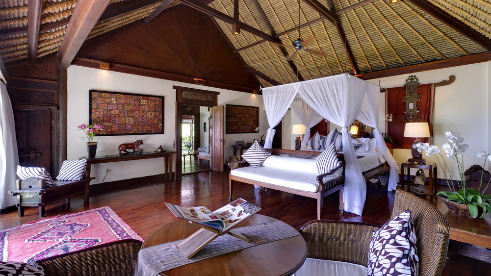 Master suite at Villa Sungai Tinggi with a canopied four-poster bed under a soaring thatched roof