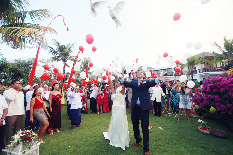 Bride and groom releasing balloons and doves on the lawn at Villa Uma Nina during their wedding celebration in Jimbaran