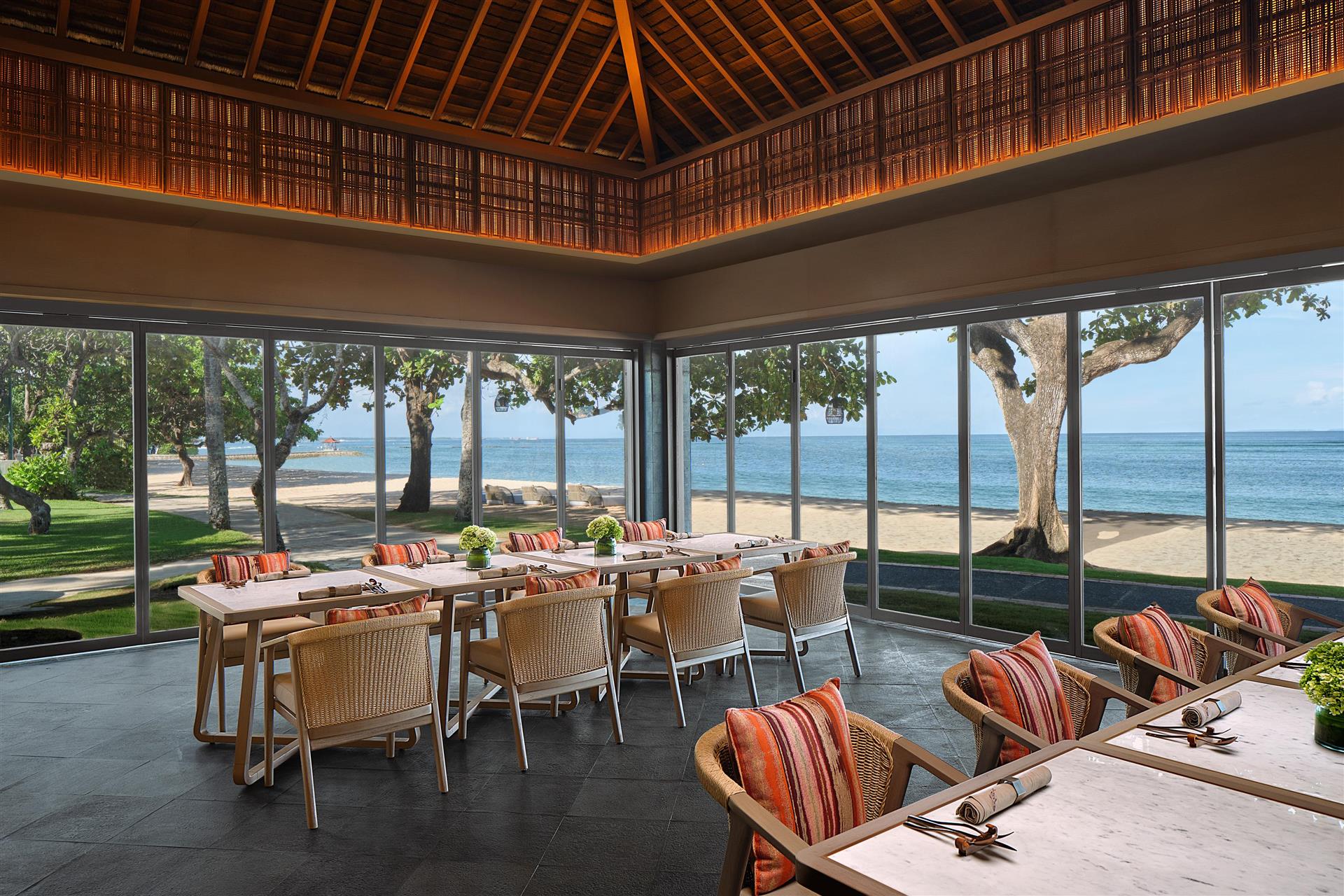 An ocean-view dining pavilion with tables set beside the beach at The Westin Resort Nusa Dua